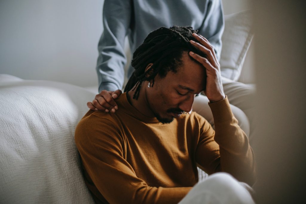 Man sitting and grieving with consoling hand